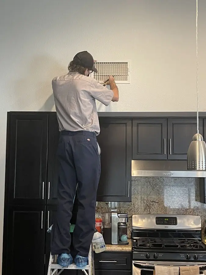 Technician inspecting an air vent during HVAC service in Gresham